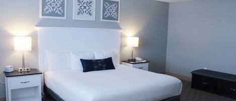 A neatly arranged hotel room with a large bed, two bedside tables, a nightstand, and a dresser.