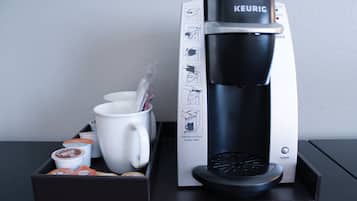 A Keurig coffee machine with a coffee pod holder, a mug, and a tray.
