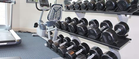 A gym with treadmills, weight benches, and dumbbells.