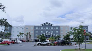 A hotel with a prominent sign, multiple parking spaces, and palm trees in the foreground.