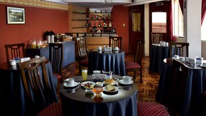 Un comedor con varias mesas, sillas y una pared de botellas de licores.