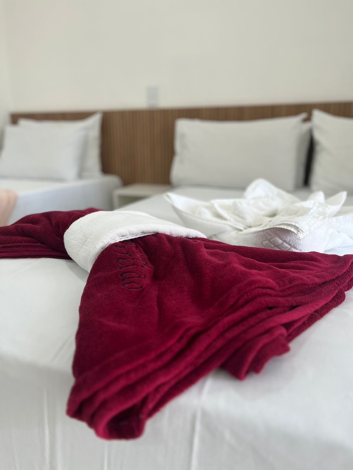 A neatly made bed with white linens and a red blanket.
