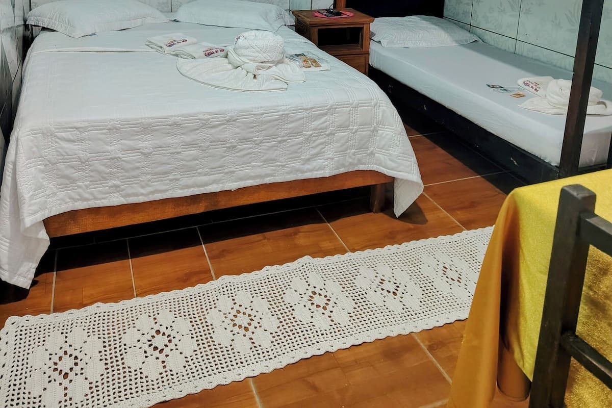 Quarto com beliche, mesa de cabeceira, tomada e ventilador de teto.