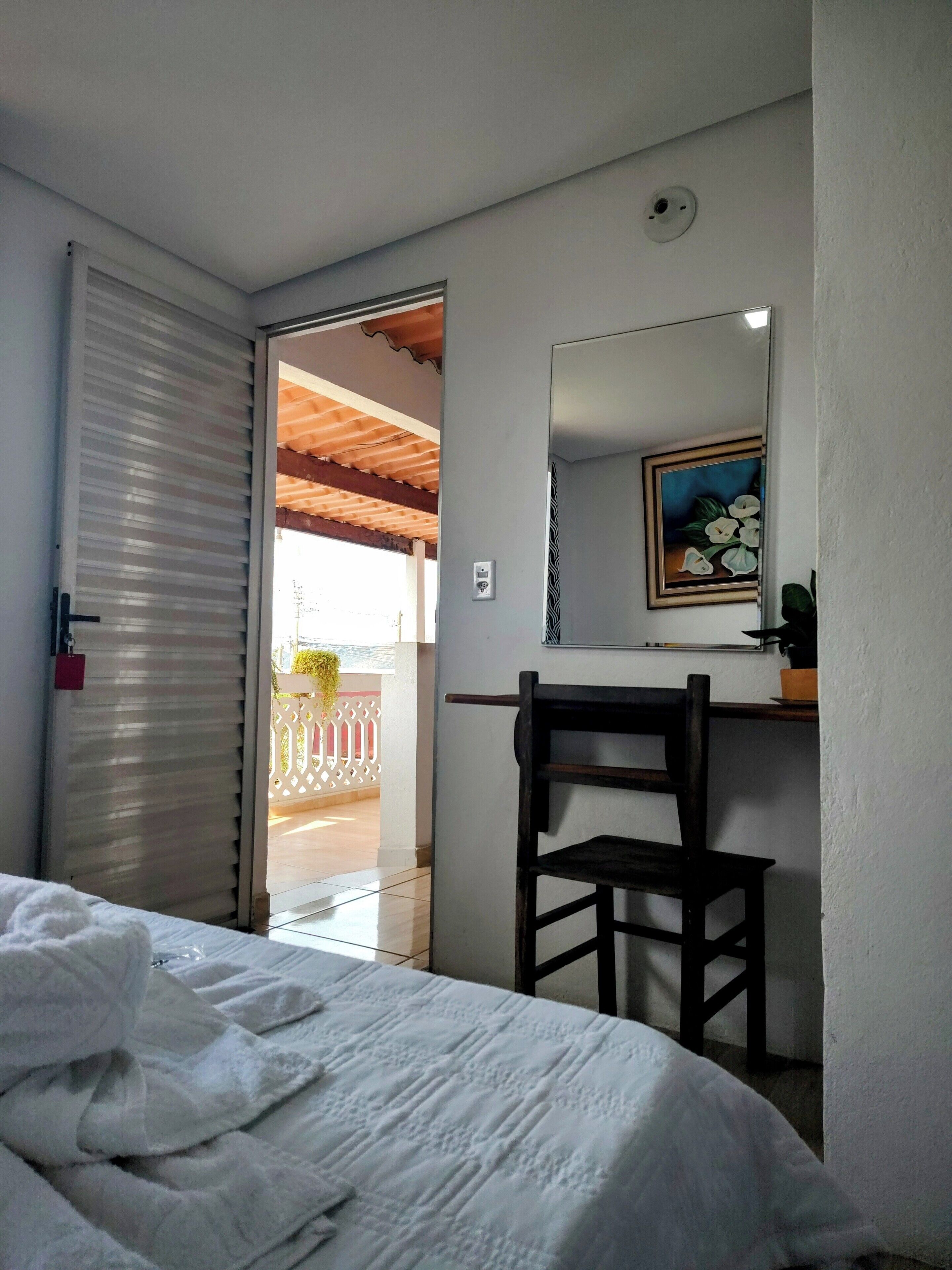 Una camera da letto con un letto, una scrivania con una sedia, uno specchio e un quadro appeso al muro.