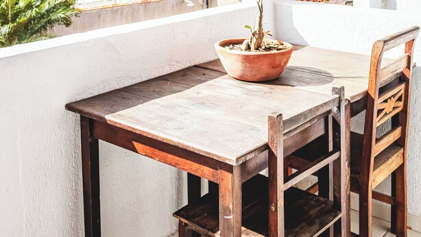 A balcony with a wooden table and chairs, a potted plant, and a view of the sea and mountains. - Pousada Aconchego Recanto Canto do Mar - São Sebastião - Caraguatatuba (São Sebastião)
