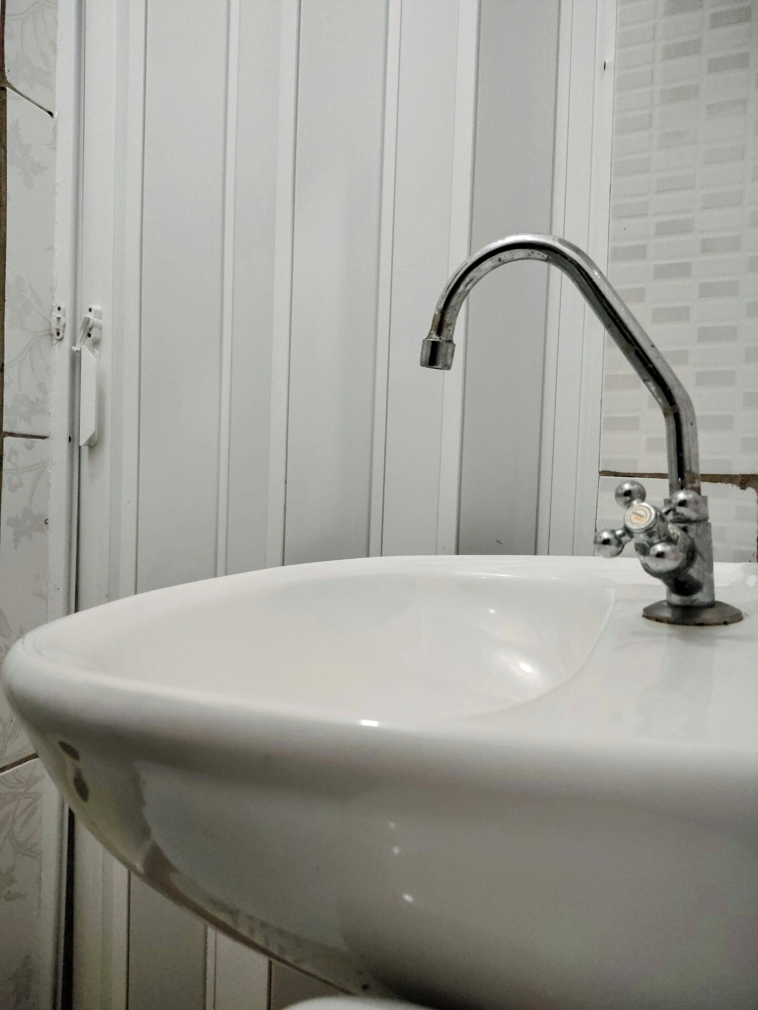 Un baño con un lavamanos blanco, un grifo de cromo y una puerta blanca con pomo.