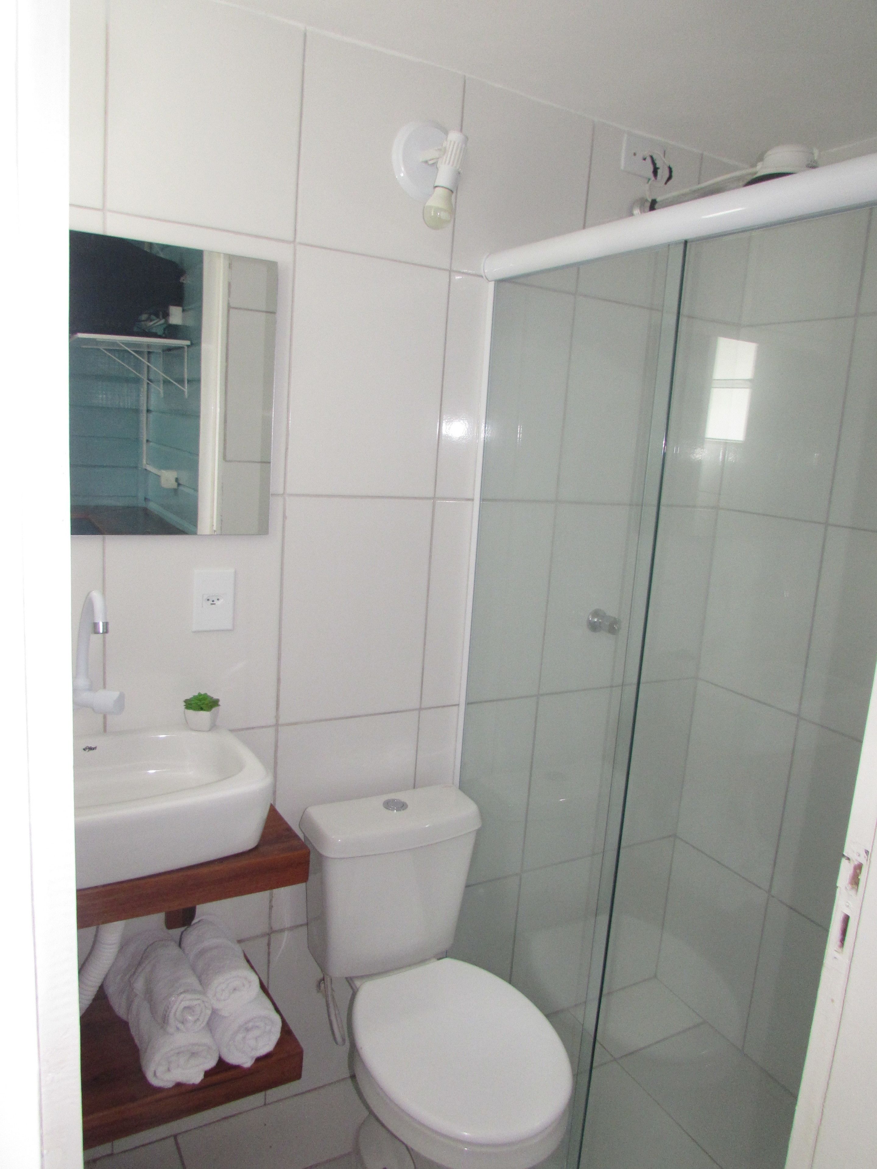 Baño con inodoro, lavamanos y cabina de ducha de vidrio.