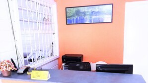 A reception desk with a calendar, a phone, and a vase of flowers. - Pousada Green House (Ubatuba)