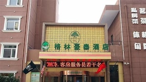 A hotel entrance with a green and yellow sign, glass doors, and potted plants. - GreenTree Inn HeFei South High-Speed Railway Station BaoHe Avenue Baohe District Government Hotel (Hefei)