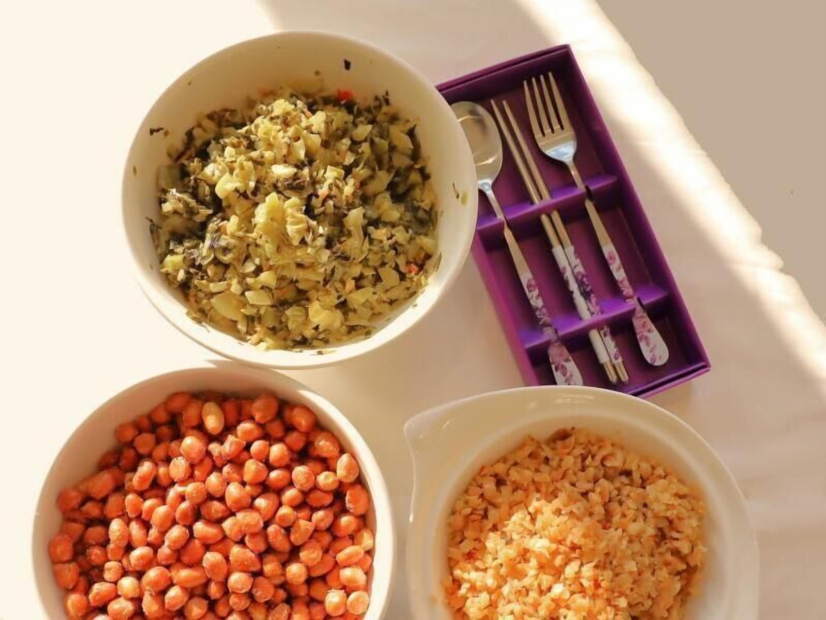 Three bowls of food on a table with a purple tray containing forks and a spoon.