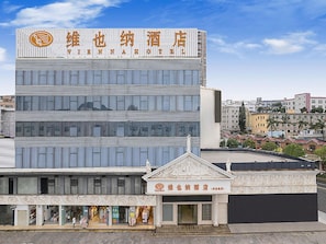Un hotel de varios pisos con fachada moderna, destacando un cartel con caracteres chinos.