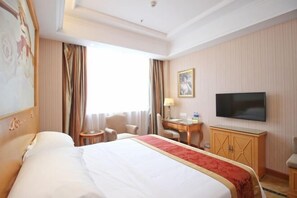 A hotel room with a large bed, a desk, a chair, a TV, and a window with curtains. - Vienna Hotel (Shenzhen Tianbao Road) (SHENZHEN)