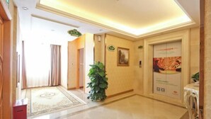 A hotel lobby with a marble floor, a reception desk, a large potted plant, and a wall-mounted elevator. - Vienna Hotel (Shenzhen Tianbao Road) (SHENZHEN)