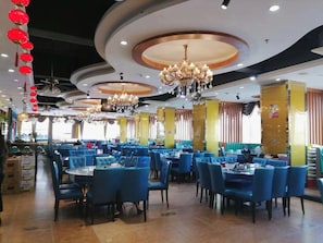 Un restaurante con varias mesas y sillas, candelabros y un techo con diseños circulares.