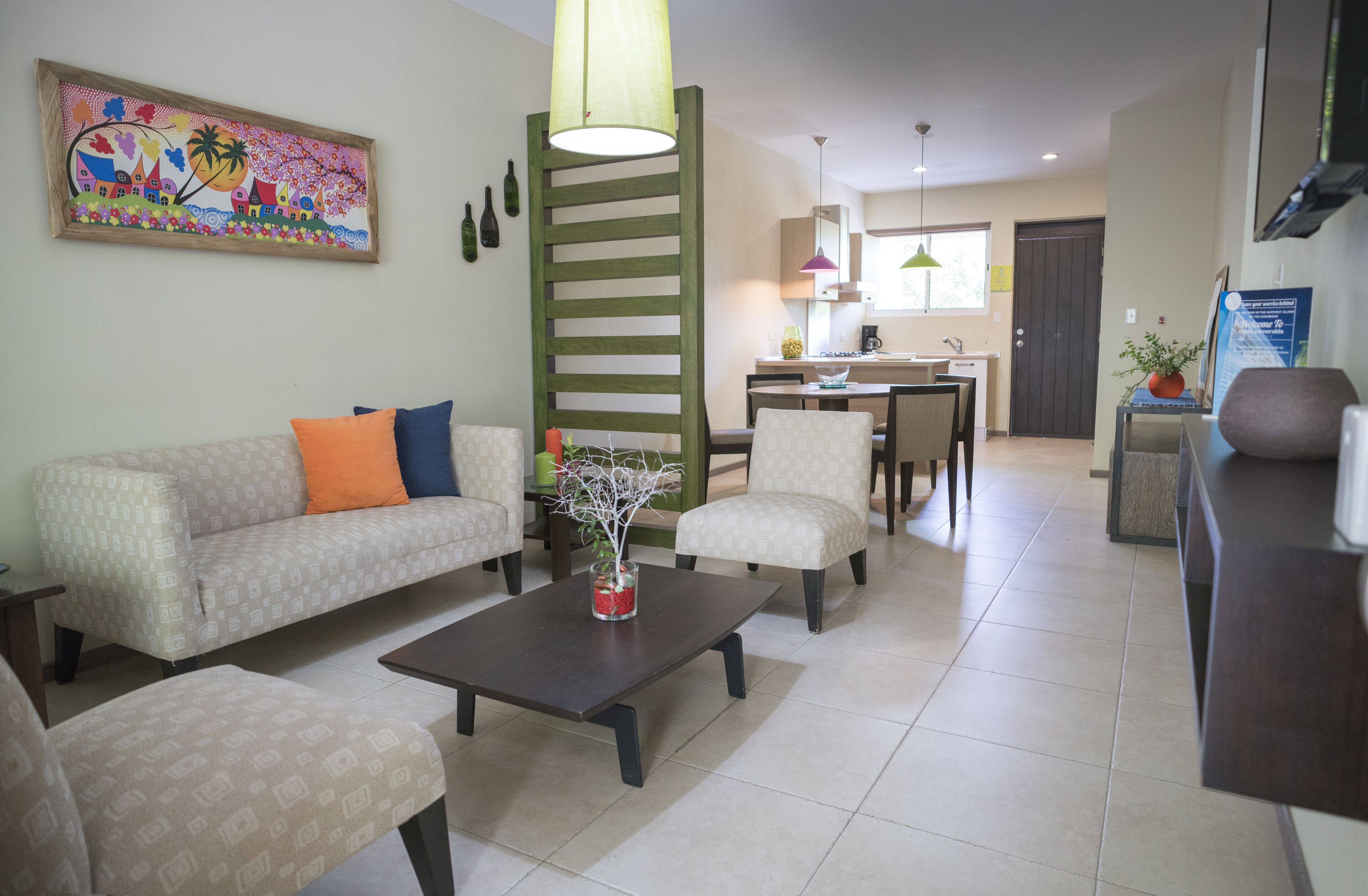 A living room with a sofa, armchairs, a coffee table, and a dining area with chairs and a table.