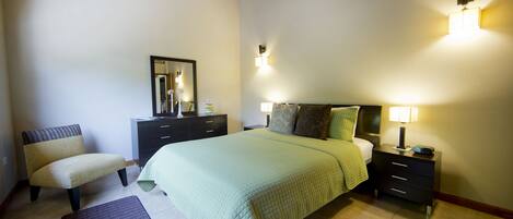 Une chambre à coucher comprenant un lit, des tables de chevet, une commode, une chaise et un miroir.