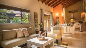 A spacious living area with a sofa, a coffee table, and a dining area with chairs and a table. - Costa Esmeralda Village (Noord)