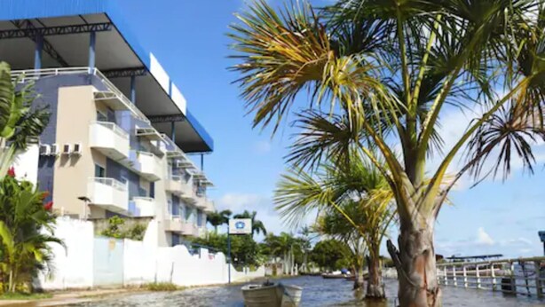 Un bâtiment situé au bord de l’eau, doté de balcons et surmonté d’un palmier en premier plan.