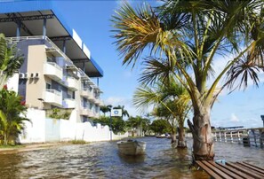 A waterfront building with balconies and a palm tree in the foreground. - Hotel Mirante da Ilha (Santarém)