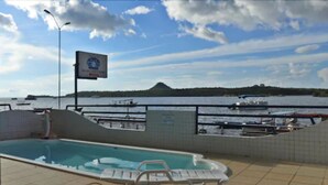 Une piscine extérieure avec des chaises longues, une vue sur l’eau et un panneau d’affichage.