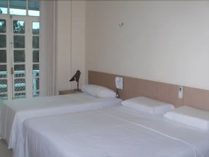 A hotel room with two single beds, a nightstand, a lamp, and a window with a view of the outside. - Hotel Mirante da Ilha (Santarém)