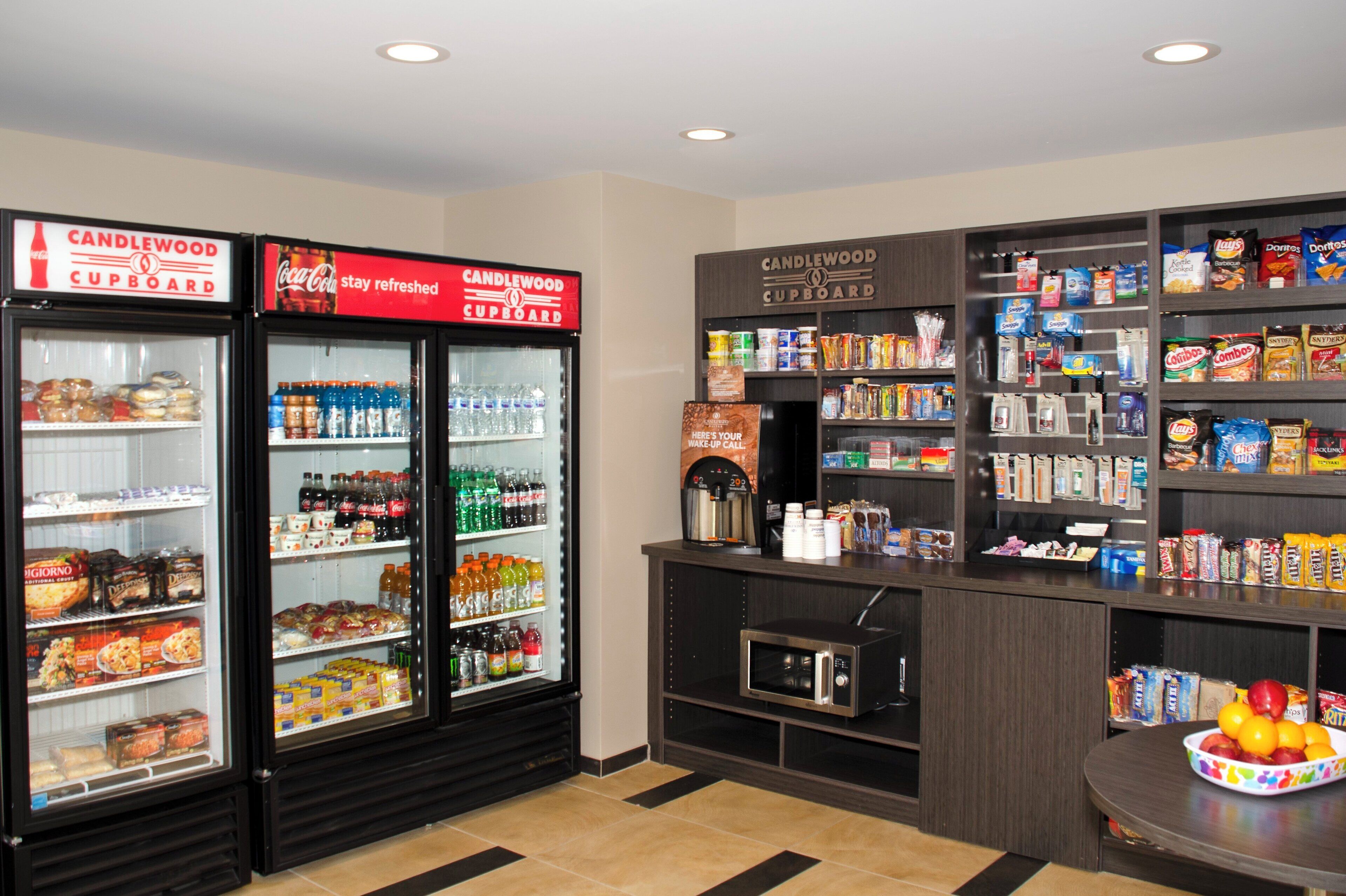 A snack and beverage area with refrigerated cases, a microwave, and shelves stocked with snacks and drinks.