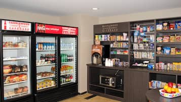 A snack and beverage area with refrigerated cases, a microwave, and shelves stocked with snacks and drinks.