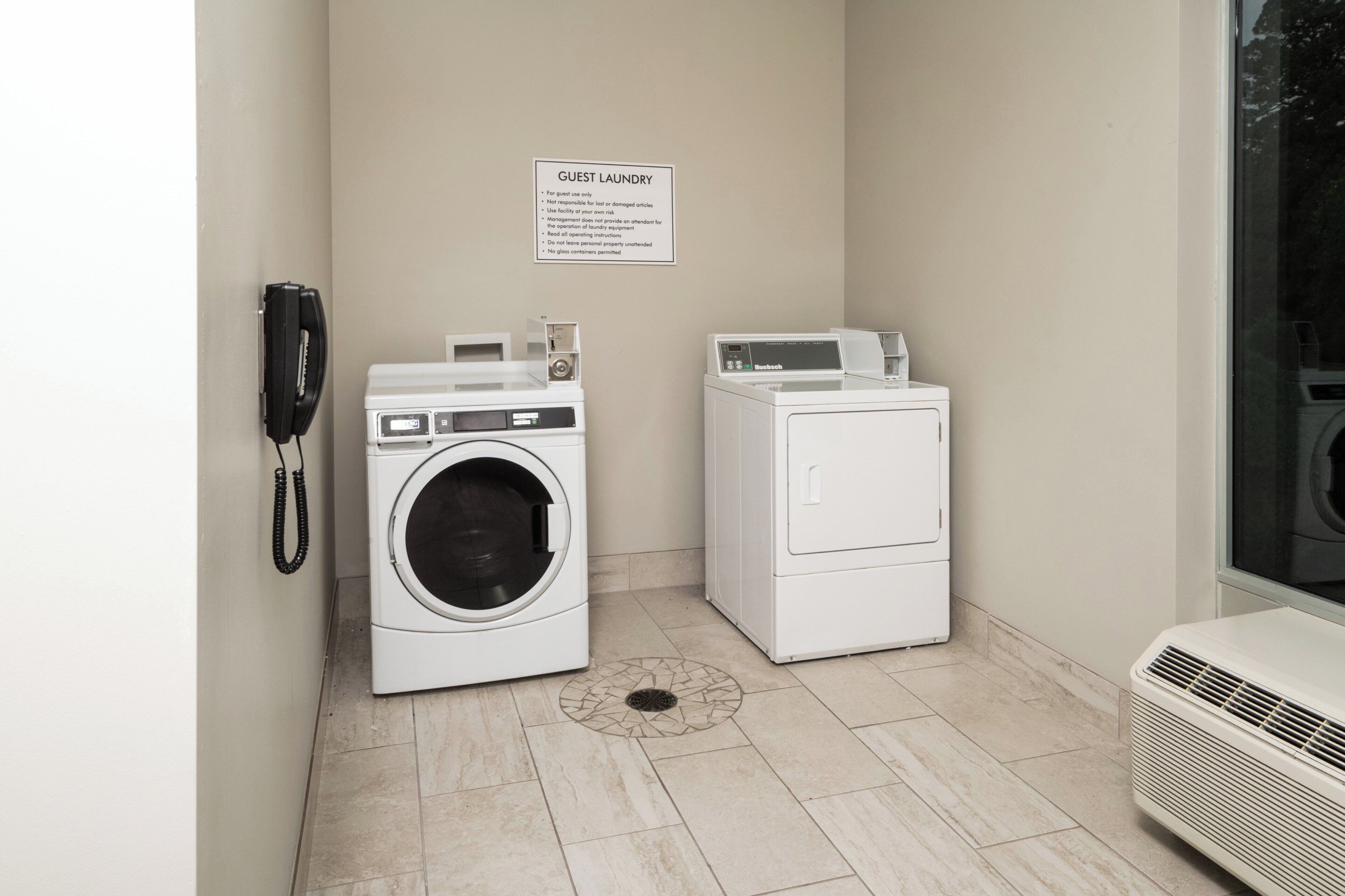 Une buanderie équipée de deux machines à laver, d’un téléphone et d’un panneau indiquant les instructions de lavage.