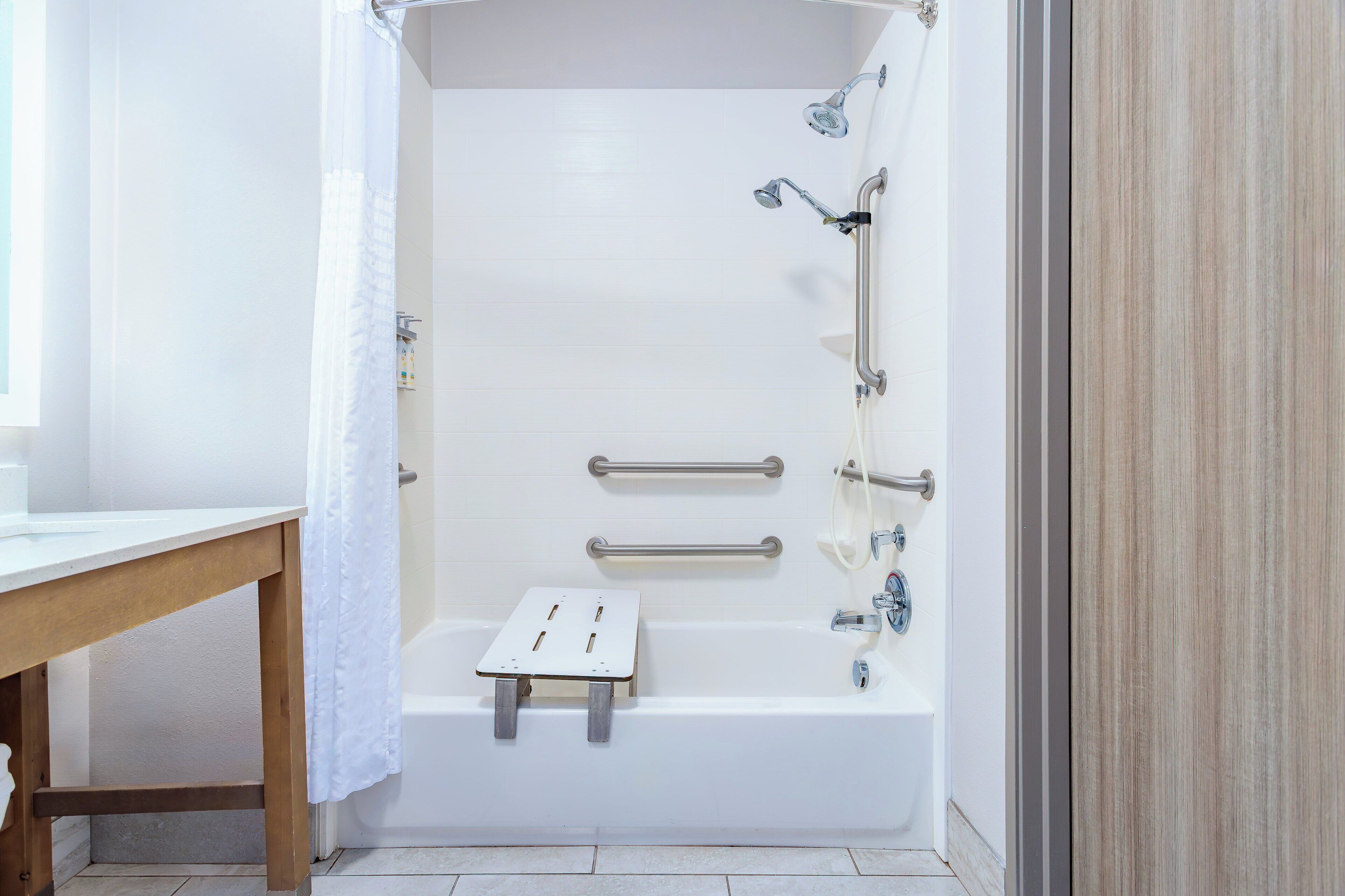 A modern bathroom with a bathtub, shower, and grab bars.