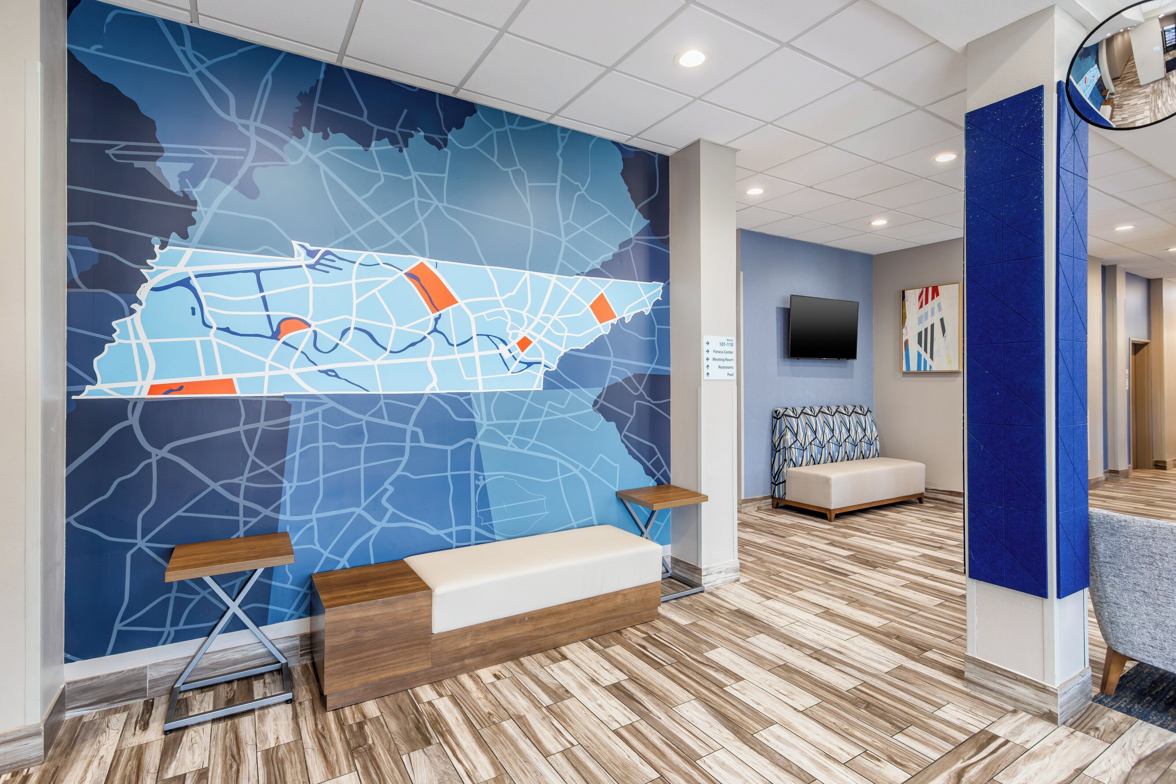 A modern lobby with a large wall map, seating area, and a TV screen.