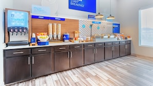 Un área de cocina moderna con barra desayunadora, secciones identificadas para fruta, cereales y alimentos calientes, y un dispensador de agua.