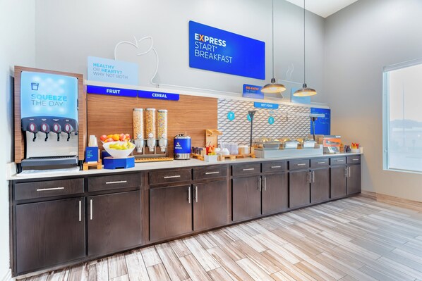 A modern kitchen area with a breakfast bar, labeled sections for fruit, cereal, and hot food, and a water dispenser.