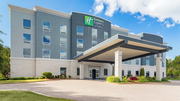 Un edificio de Holiday Inn Express de diseño moderno, con un acceso cubierto y un jardín delantero ajardinado.