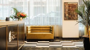 A hotel reception area with a checkered floor, a sofa, a reception desk, and a framed artwork on the wall. - Hotel Indigo Kansas City Downtown by IHG (Kansas City)