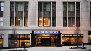 Ein Hotel mit einer modernen Fassade, großen Fenstern und einem auffälligen Eingang mit einem Neonzeichen.