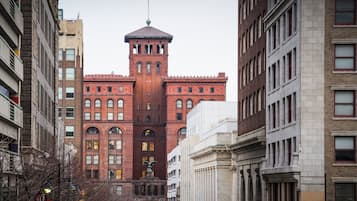 A red brick building with a central tower and arched windows, surrounded by modern buildings.