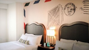 A hotel room with two beds, a nightstand with a lamp, and a wall with a welcome sign and a stamp. - Hotel Indigo Kansas City Downtown by IHG (Kansas City)