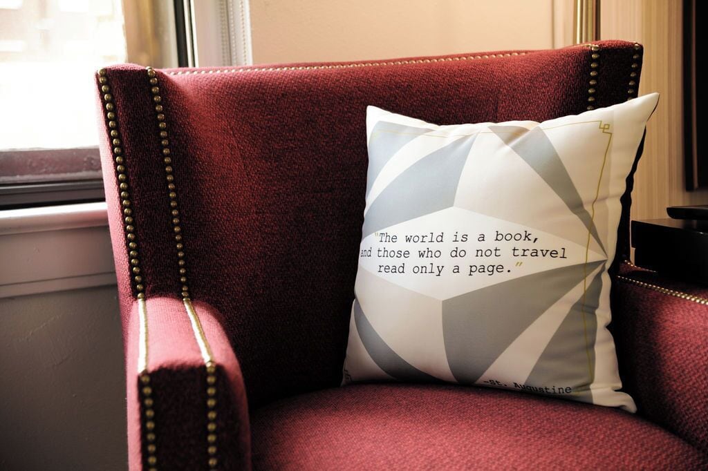 A red upholstered chair with a cushion featuring a quote.