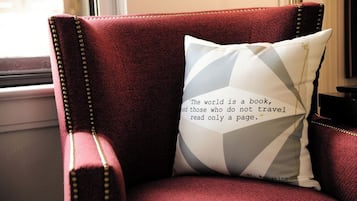 A red upholstered chair with a cushion featuring a quote.