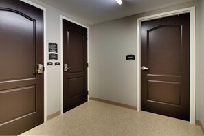 Un couloir avec trois portes marron, chacune portant une pancarte indiquant la présence d ’un casier de rangement.
