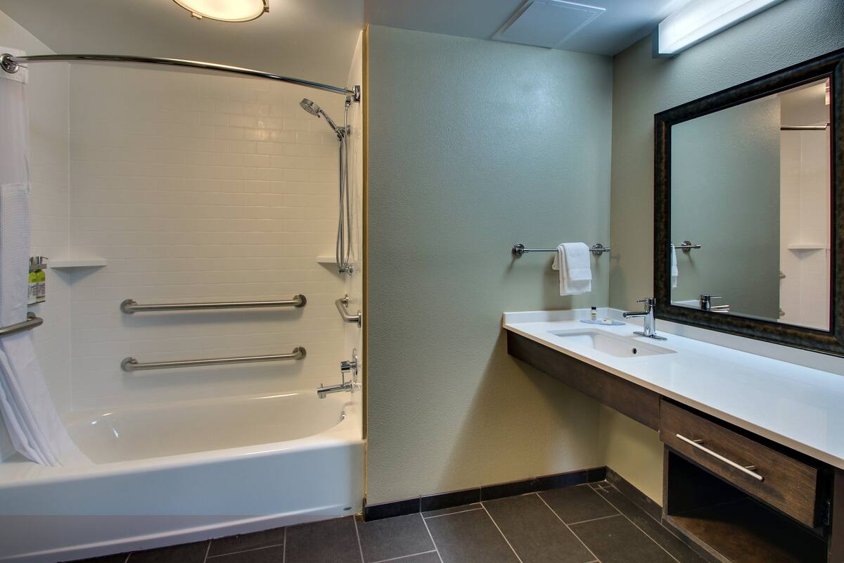 Une salle de bain équipée d’une baignoire, d’un lavabo, d’un miroir et d’un porte-serviettes.