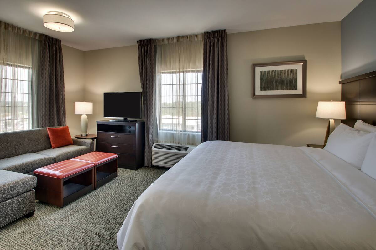 Une chambre d’hôtel avec un lit, un canapé, une télévision, un bureau et une lampe.