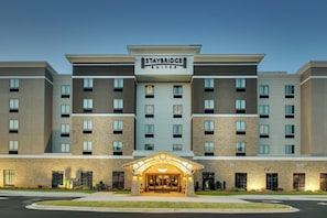 Un hôtel Staybridge Suites doté d’une façade moderne, de plusieurs étages et d’une entrée bien éclairée.
