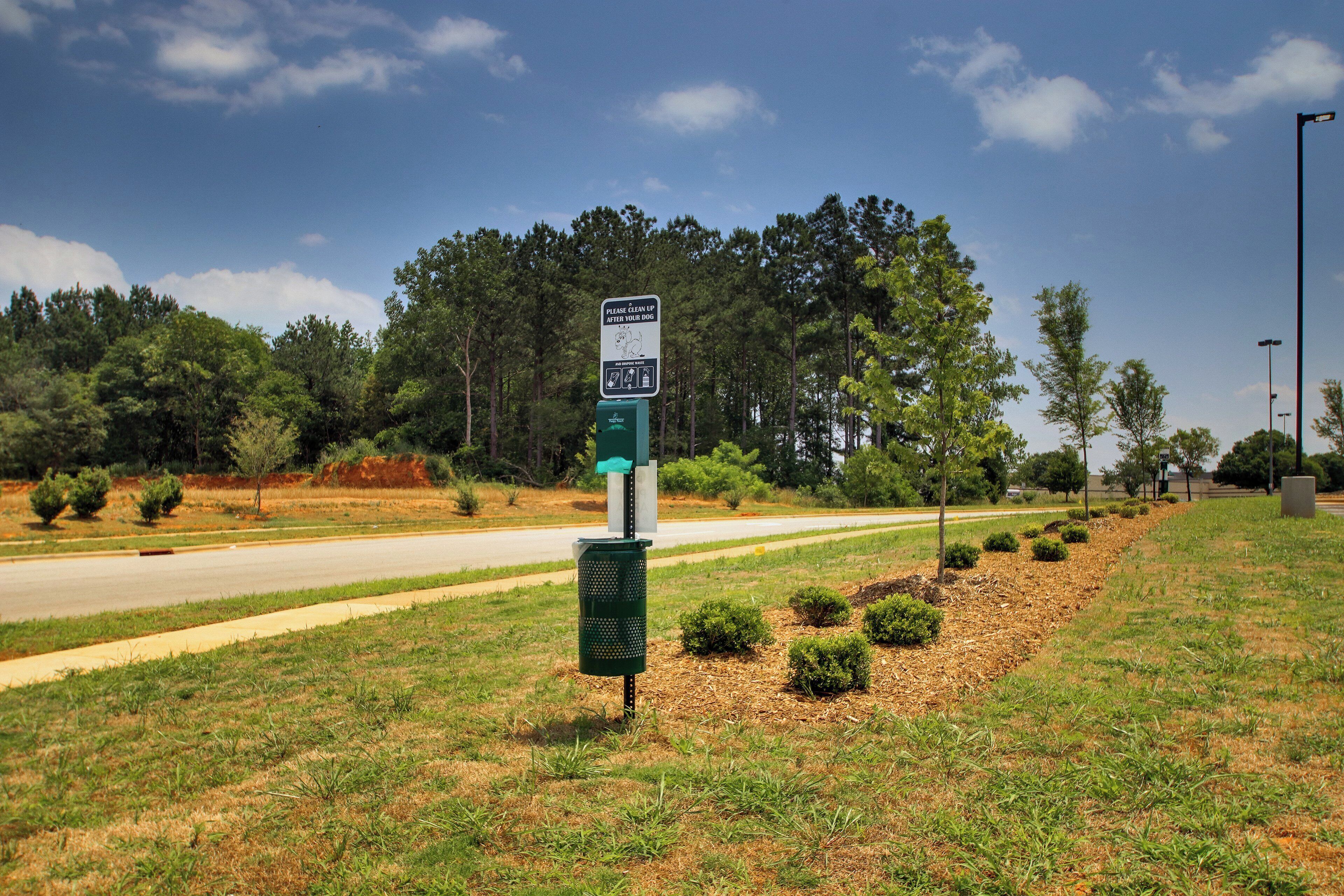 A roadside sign with a dog waste disposal bin.