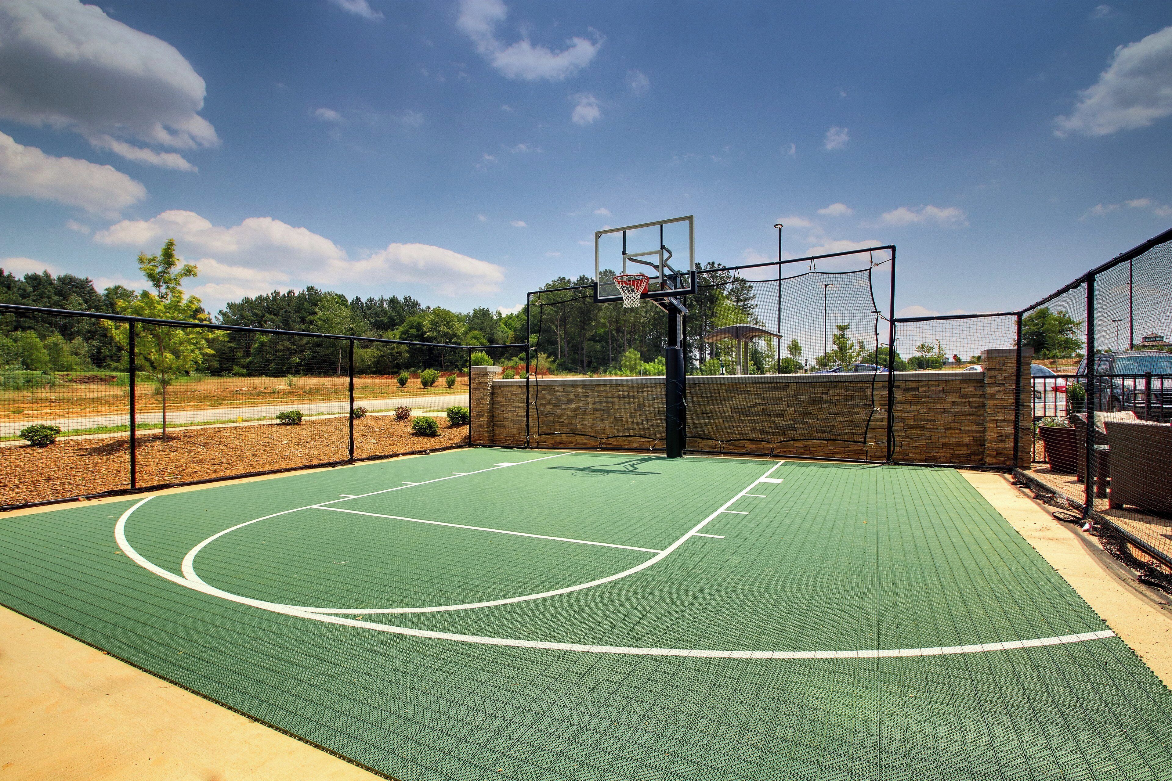 An outdoor basketball court with a net, a hoop, and a clear sky.