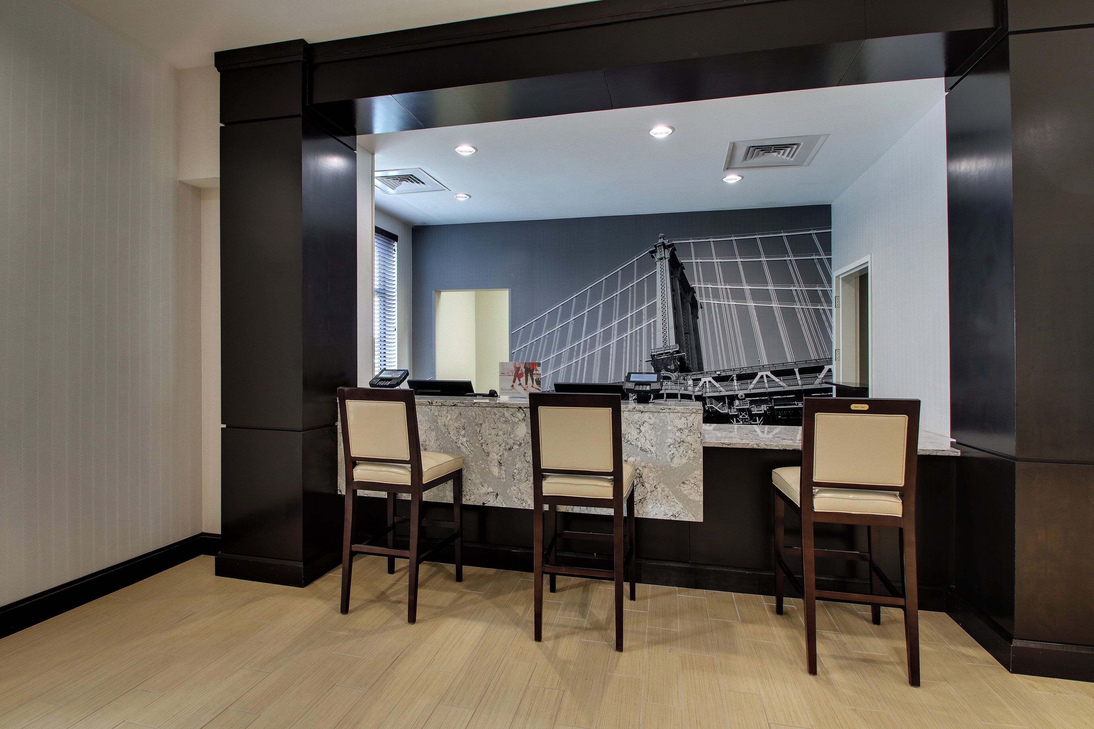A bar area with a counter, three chairs, and a large mirror reflecting the interior.