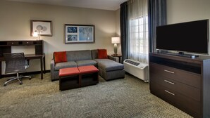 Une chambre d’hôtel équipée d’un canapé, d’un bureau, d’une télévision et d’une lampe.