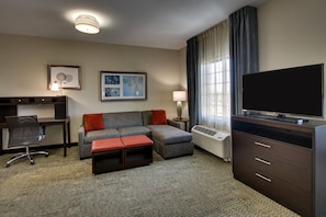 Habitación de hotel con sofá, escritorio, televisor y lámpara.