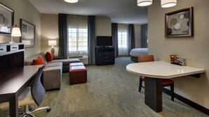Une chambre d’hôtel équipée d’un bureau, d’un canapé, d’une table à manger, d’une télévision et d’un lit.