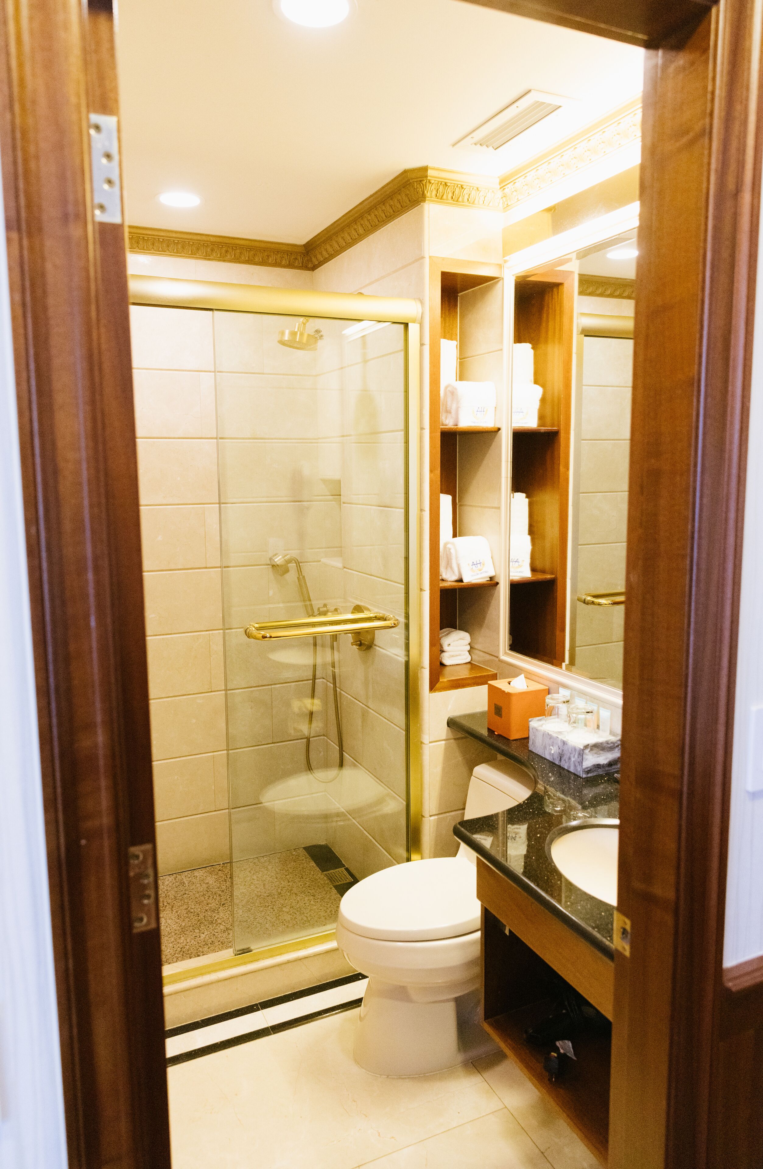 Ein Hotelbad mit einer Duschkabine, einer weißen Toilette und einem Waschtisch mit Spiegel und Ablageflächen.